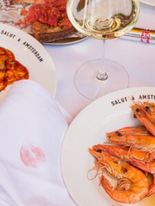 Gedekte tafel op het terras van Salut met crevettes, tomaten en witte wijn, om de hoek van de Albert Cuypmarkt