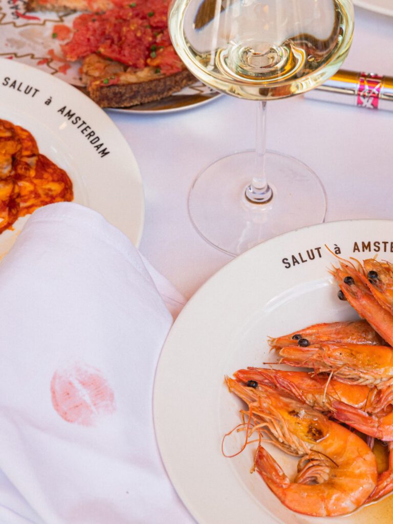 Gedekte tafel op het terras van Salut met crevettes, tomaten en witte wijn, om de hoek van de Albert Cuypmarkt