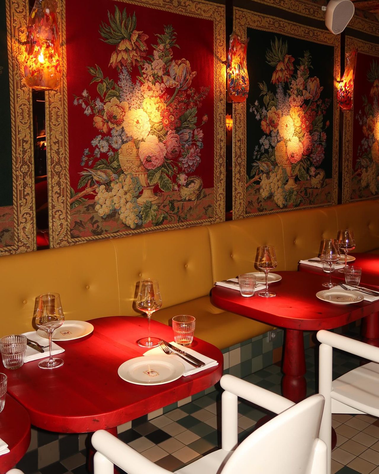 Interior of Salut with red tables, a yellow banquette and floral tapestries, designed by Jean-Philippe Demeyer